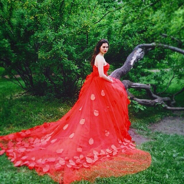 red, growth, plant, front view, tree, grass, green color, nature, flower, person, day, human representation, outdoors, young adult, standing, looking at camera, portrait, lifestyles