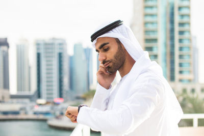 Portrait of young man standing against buildings in city