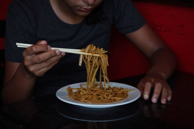 Midsection of woman eating noodles 