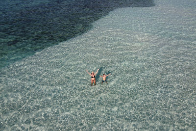 Mother and son waving from turquoise waters in the maldive islands