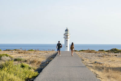 Rear view of people walking on sea shore against sky