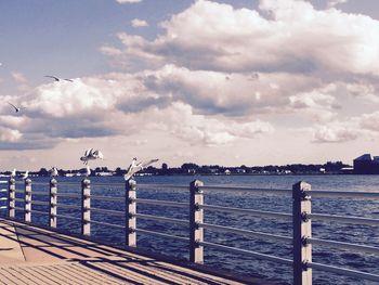 Pier on sea against cloudy sky