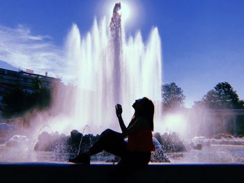 Silhouette woman sitting against fountain