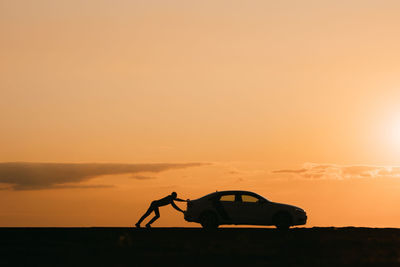 Silhouette people standing on land against sky during sunset