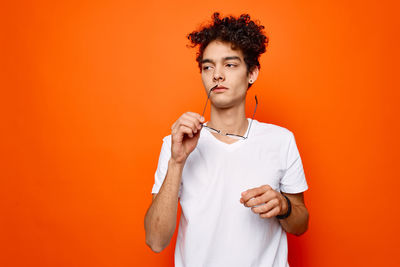 Portrait of man standing against orange background