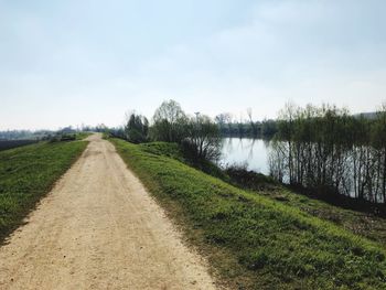 Road by canal against sky