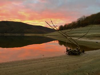 Scenic view of lake against dramatic sky during sunset