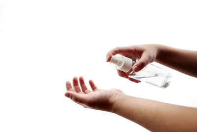 Close-up of woman hand holding bottle against white background