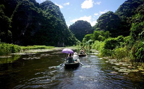 People in boat on river against sky