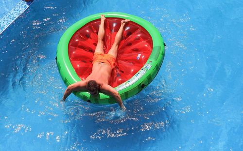 High angle view of shirtless man with pool raft floating on swimming pool