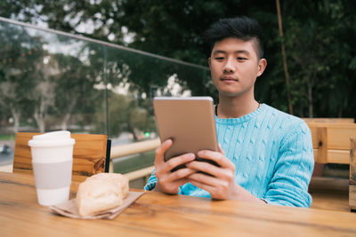 Young man using mobile phone while sitting on table