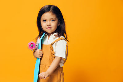 Portrait of young woman against yellow background