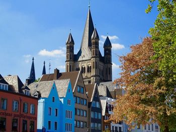 Low angle view of buildings and cologne cathedral in germany against a blue sky