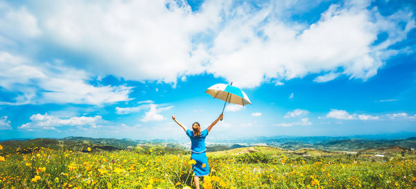 Rear view of woman standing on field against sky