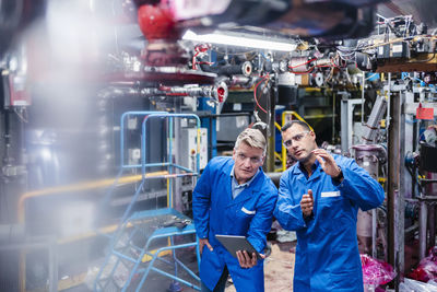 Male technician explaining strategy to colleague with digital tablet in industry