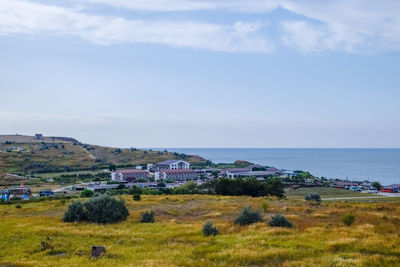 Houses on field by buildings against sky