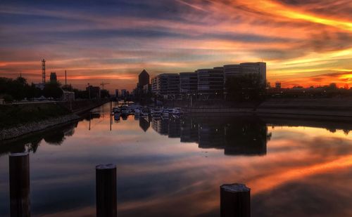Reflection of buildings in city against sky during sunset