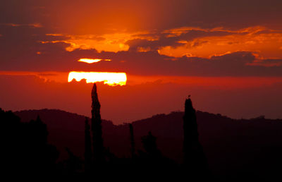 Silhouette built structure against dramatic sky during sunset