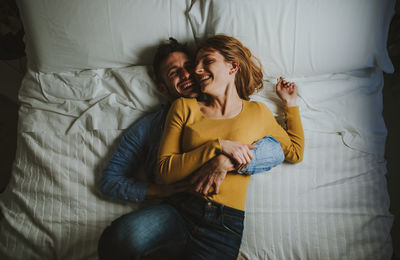 High angle view of couple embracing while lying on bed at home