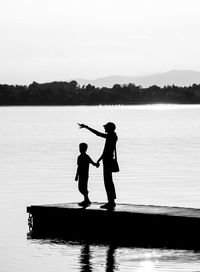 Silhouette men standing in lake against sky