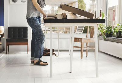 Low section of man standing on table at home