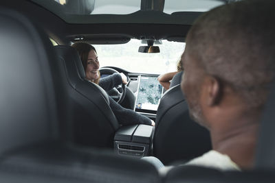 Smiling woman looking at man while driving electric car