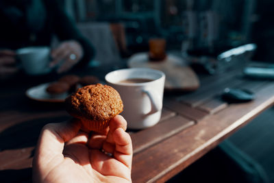 Close-up of hand holding cake on table