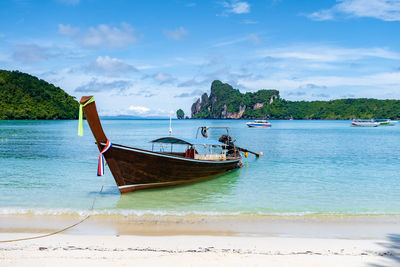 Boat moored on beach against sky