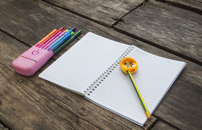 Close-up of colored pencils and book on table