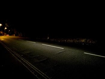 Empty road along countryside landscape at night