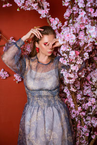 Studio shot of beautiful woman who smells of flowers, enjoying pleasant scent