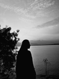 Rear view of silhouette man standing by tree against sky