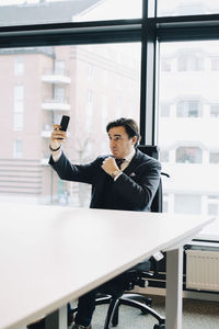 Businessman taking selfie while sitting at desk in office