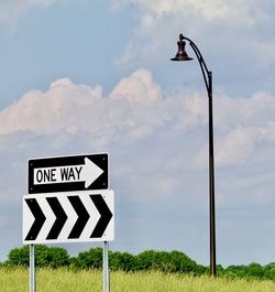 Road sign on street against sky