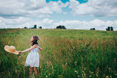 Girl in wildflower field against blue summer sky
