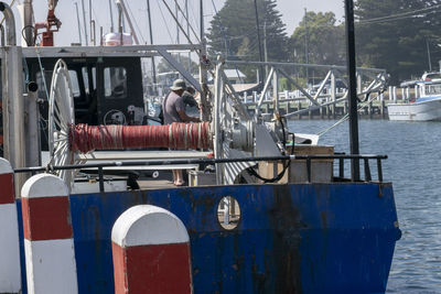 Man sitting on pier at harbor