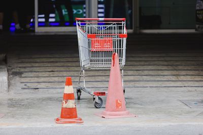 Empty shopping cart with traffic cone on road