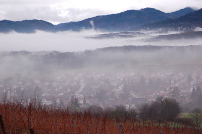 Townscape by mountains during foggy weather