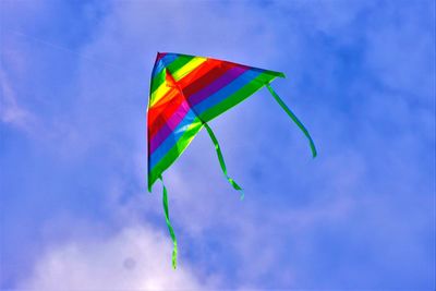 Low angle view of rainbow flag kite against blue sky