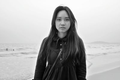 Portrait of young woman standing on shore at beach