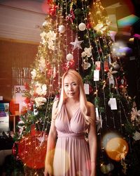 Young woman standing by christmas tree