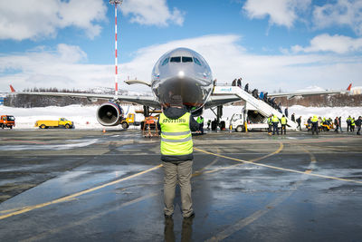 Rear view of man standing on airplane against sky