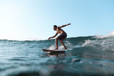 Full length of shirtless man in sea against clear sky