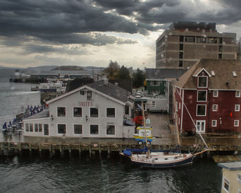 Buildings by river against sky