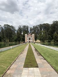 Footpath in park against cloudy sky