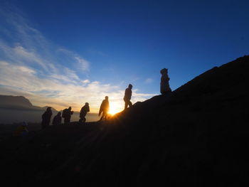 Silhouette people on mountain against sky during sunset