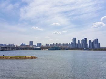 Sea by buildings against sky in city