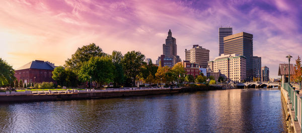 River by buildings against sky during sunset