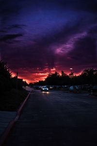 Cars on road against dramatic sky at sunset