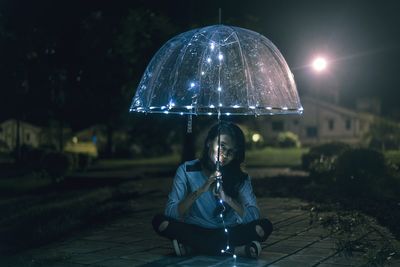 Young woman sitting outdoors at night